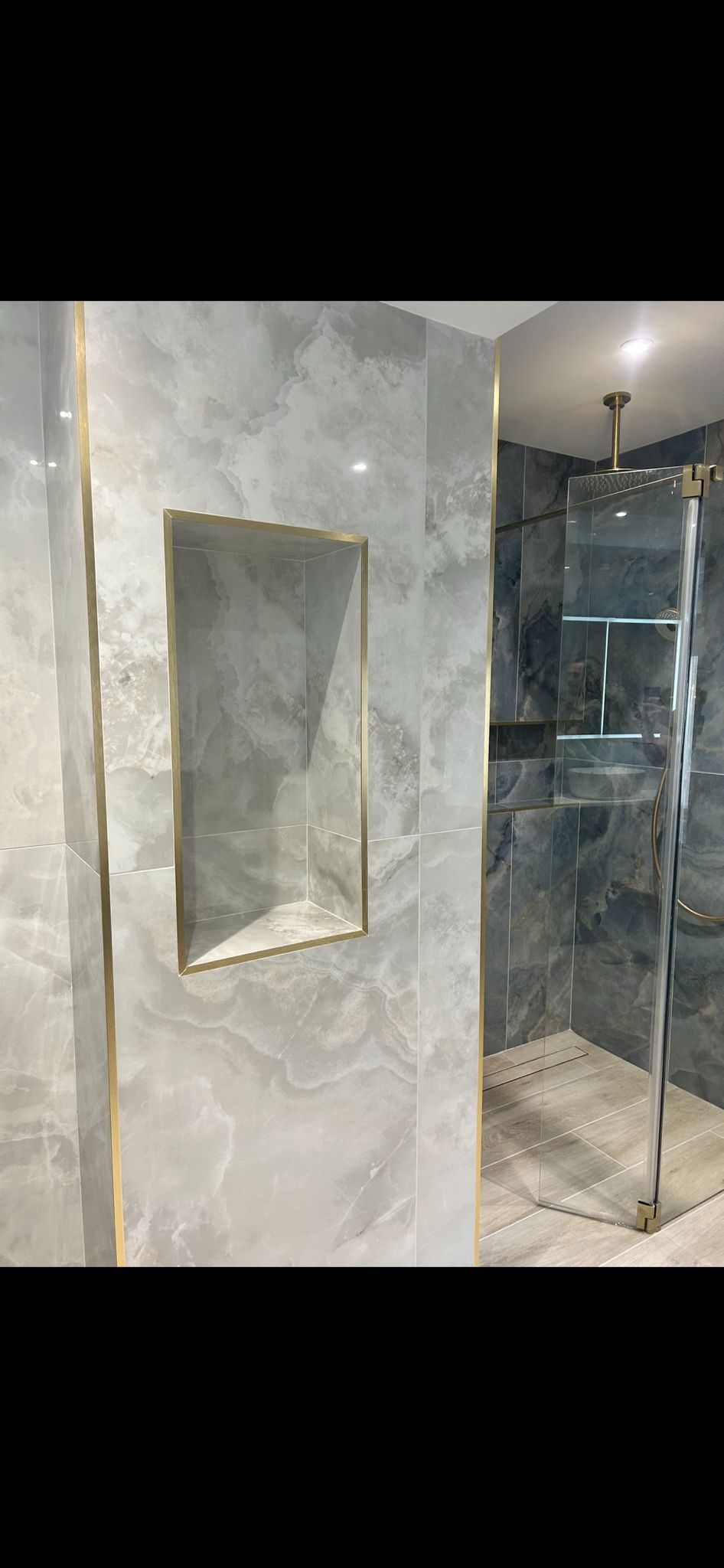 Walk-in shower with gold niche and marble tiling