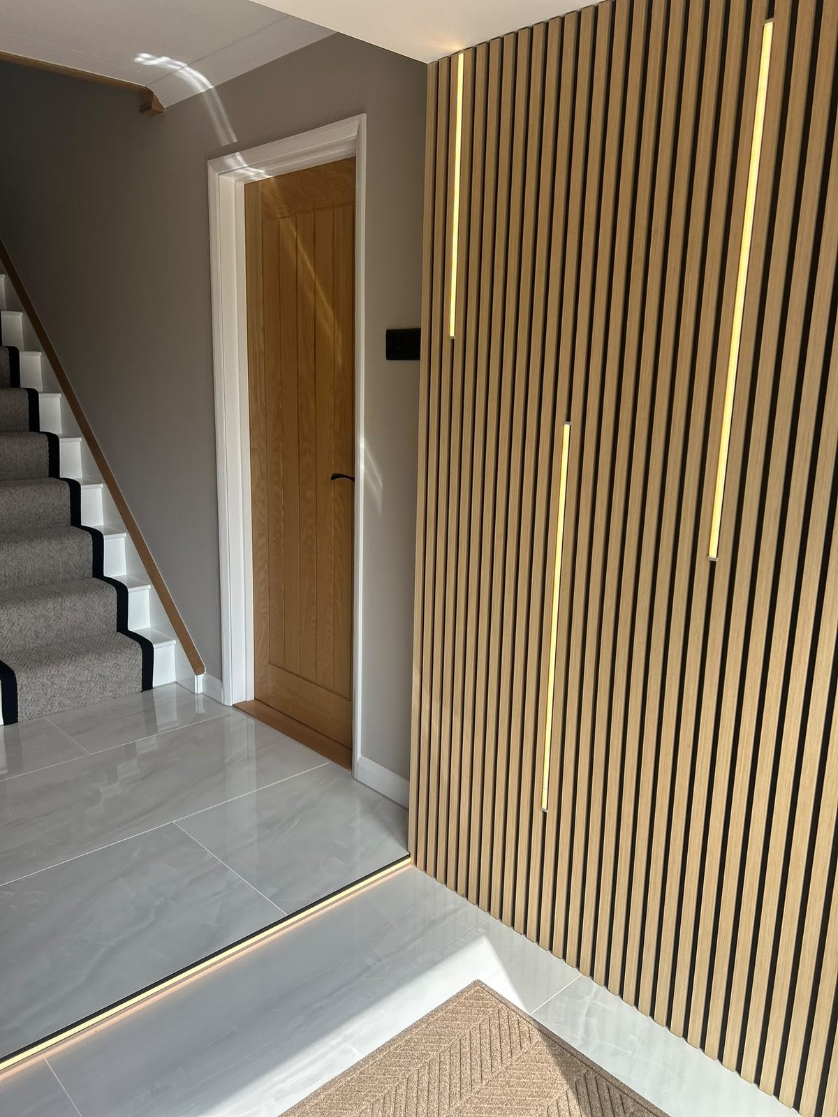 Rebuilt staircase in grey carpet with white risers beside the slatted wall