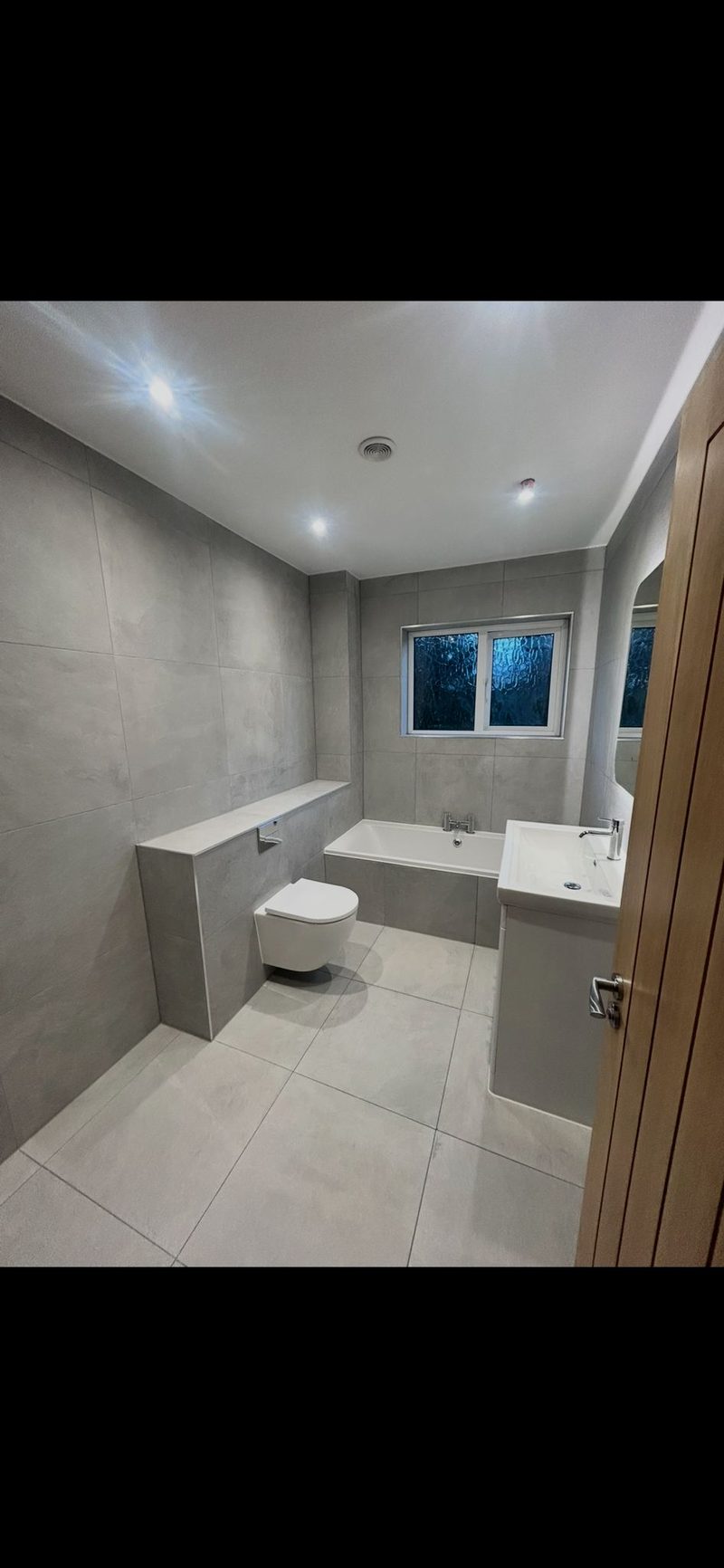 Grey tiled bathroom with built-in bath