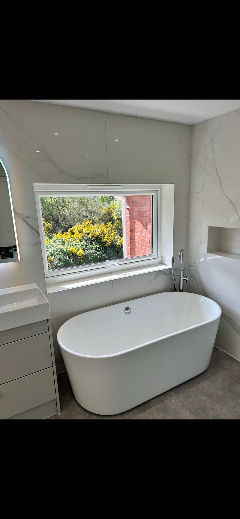 Freestanding bath with marble walls and garden view
